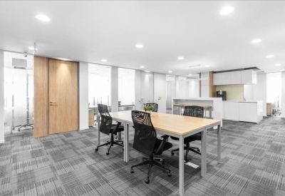 Spacious open-plan coworking area with a view of the office kitchen.