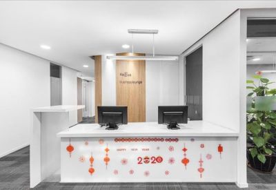 Clean white reception desk featuring festive red decorations and a branded backdrop.