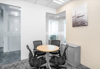 Small breakout area with a round wooden table and four mesh office chairs.
