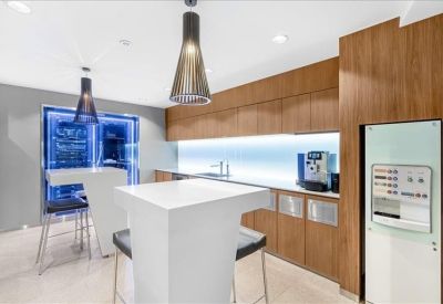Modern office kitchen and breakout area with wood cabinetry and high-top tables.