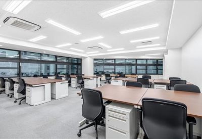 Spacious open-plan workspace with multiple desk banks and large windows.