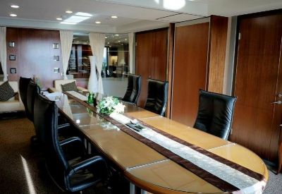 Executive boardroom featuring a long wooden table, black leather chairs, and wood-paneled walls.