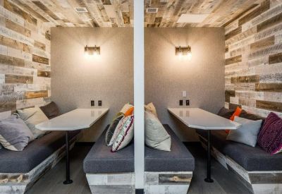 Private acoustic work booths with wood-paneled walls and comfortable cushioned seating.