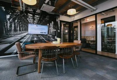 Meeting room with a round wooden table, chalkboard wall, and glass partitions.