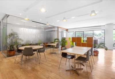Spacious communal area with multiple tables, wood flooring, and indoor plants.