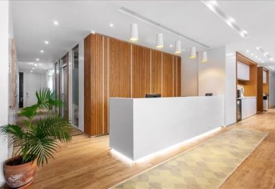 Sleek white reception desk with wood paneling and indoor greenery.