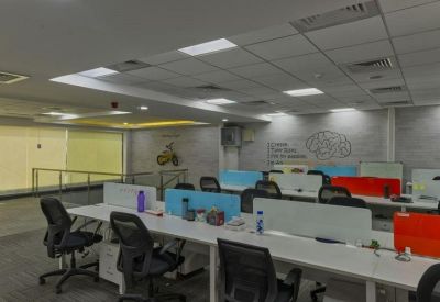 Modern open-plan office space with white desks, ergonomic black chairs, and blue privacy screens.