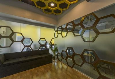 Lounge area with a dark sofa and a unique honeycomb-patterned glass partition.