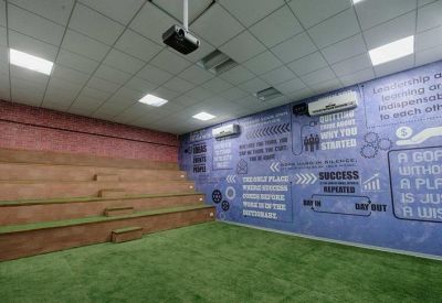 Amphitheater-style presentation room with wooden tiered seating and a purple motivational wall.