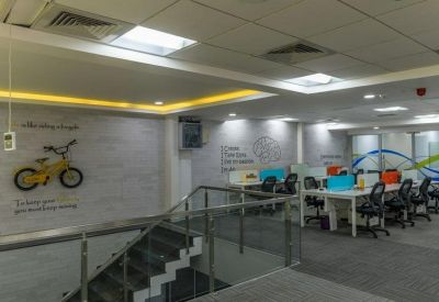 Modern coworking space with a bicycle wall graphic and staircase leading to desk rows.