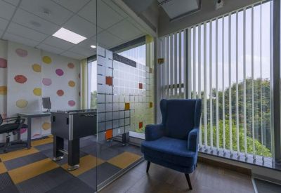 Breakout area with a blue armchair, foosball table, and colorful dot-patterned wallpaper.