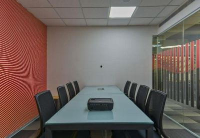 Professional meeting room featuring a frosted glass wall with red accents and a sleek conference table.