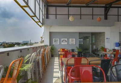 Rooftop terrace at Indiqube Vascon Almonte with colourful metal chairs and views over the city.