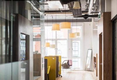 Light-filled hallway featuring wooden floors, stylish pendant lamps, and colorful privacy booths.