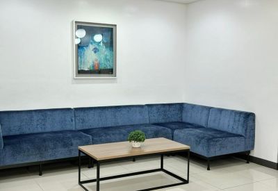 Waiting area with a long blue velvet sectional sofa and modern art piece.