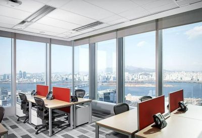 Open-plan office with desks featuring red privacy screens and panoramic city views.