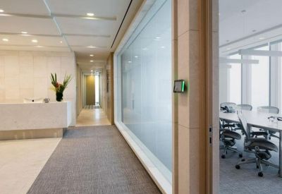Hallway viewing an internal glass-walled meeting room with mesh chairs.