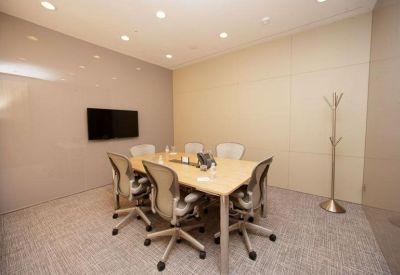 Small private meeting room with a wooden table and wall-mounted television.