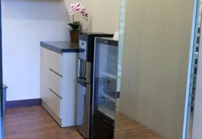 Communal area with wooden flooring and a small fridge.