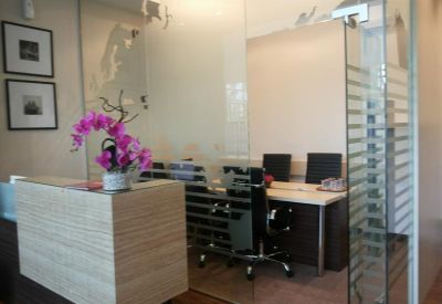 Reception area with a desk and orchids in a vase.