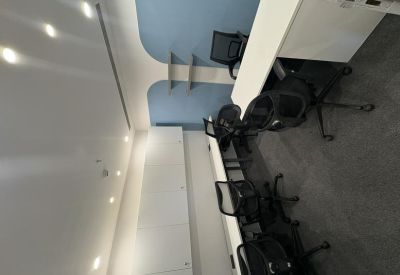 Modern open-plan workspace featuring several black mesh ergonomic chairs and long white desks.