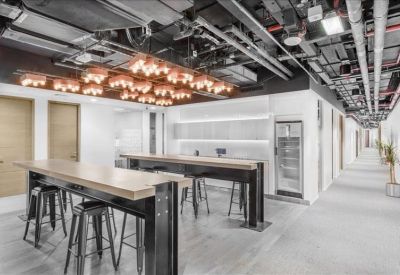 Modern breakout area with high-top wooden tables and industrial-style exposed ceiling.