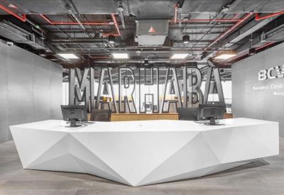 Sleek geometric white reception desk with large Marhaba signage in the background.