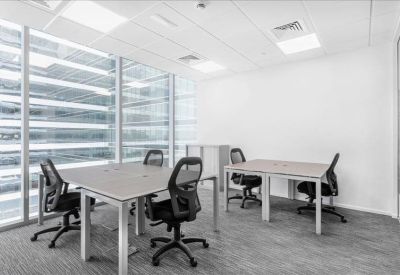 Bright four-person office suite with light wood desks and large windows.