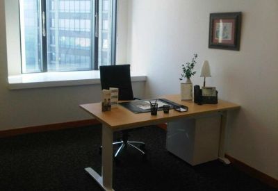 Private office suite featuring a wooden desk, ergonomic chair, and large window.
