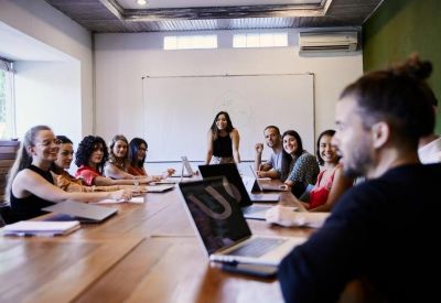 Bright conference room with a large wooden table and a white board for presentations.