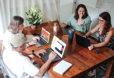 Four people collaborating at a large communal desk in a bright, airy workspace.