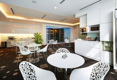 Modern office breakroom and kitchen area with white cabinetry and circular dining tables.