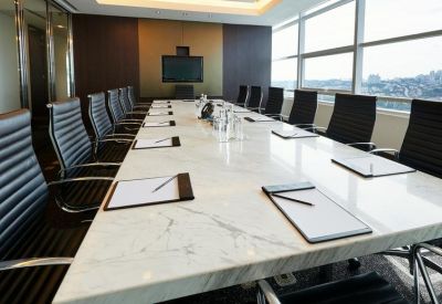 Executive boardroom featuring a long white marble table and ergonomic black leather chairs.