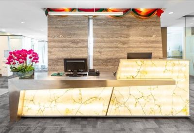 Contemporary reception desk with a glowing stone front and a vibrant orchid arrangement.