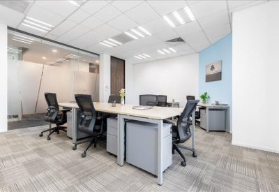 Spacious open-plan office with white desks, ergonomic black chairs, and a glass-walled conference room.