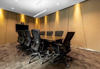 Professional meeting room with a long dark table, black chairs, and warm recessed wall lighting.