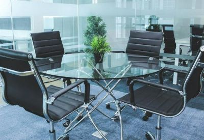 Small meeting room with a round glass table, four black chairs, and transparent glass walls.