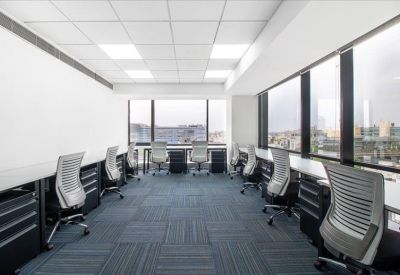 Open-plan coworking area with rows of workstations and large windows.