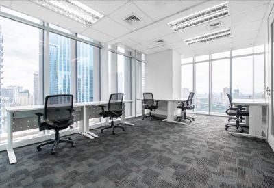 Bright open-plan workspace with rows of desks and floor-to-ceiling windows.
