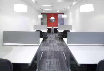 Bright open-plan office space with white desks and grey privacy partitions.