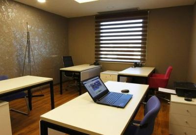 Private office suite featuring four white desks, blue and red chairs, and a textured gold accent wall.