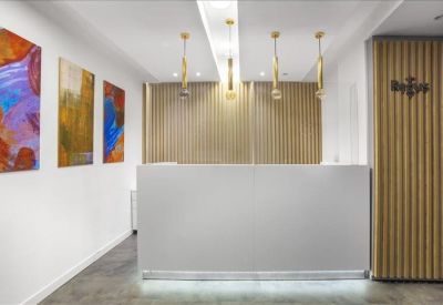 Professional reception area with a sleek white desk and colorful abstract wall art.