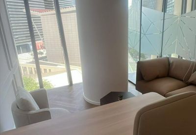 Modern office interior featuring a large white pillar, desk, and lounge area with city views.
