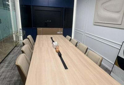 Long wooden boardroom table with grey executive chairs and a minimalist wall sculpture.