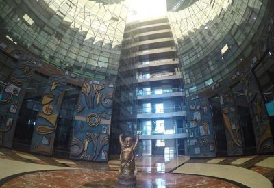 Dramatic high-ceiling lobby of the Kaledonia HDIL Building with colorful wall murals and central sculpture.