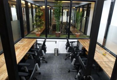 Private office pod with four workstations and wooden desks separated by glass walls.