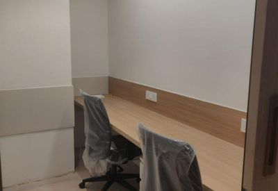 Narrow two-person workstation with light wood desk and white walls.