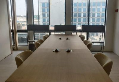 Long wooden boardroom table with light green chairs and large windows.