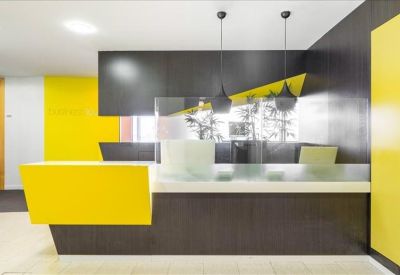 Vibrant reception desk in grey and yellow with minimalist pendant lighting.