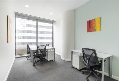 Bright corner office with three ergonomic workstations and city views.